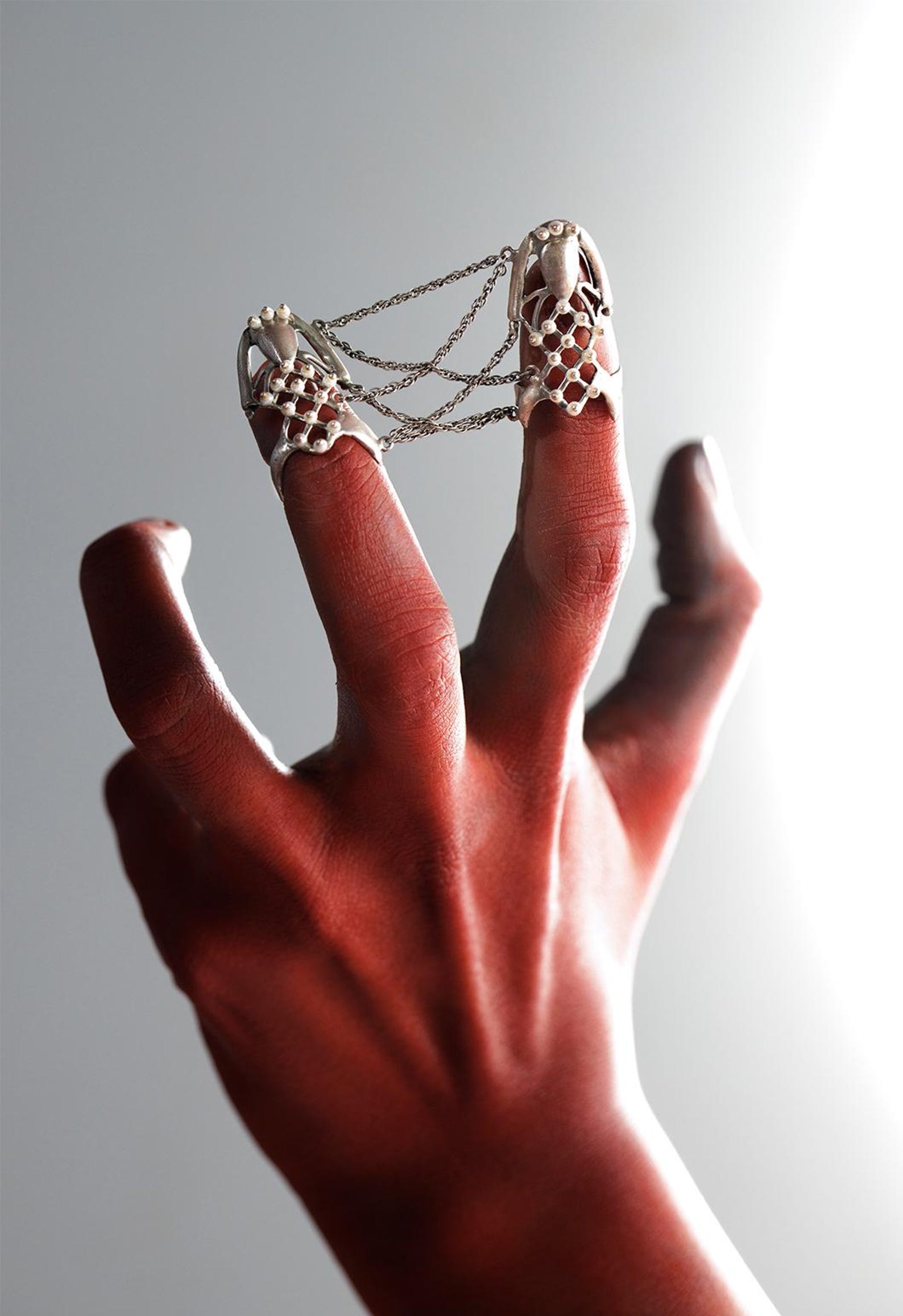 Sterling silver spiderweb finger chain ring spanning two fingers with pearl accents