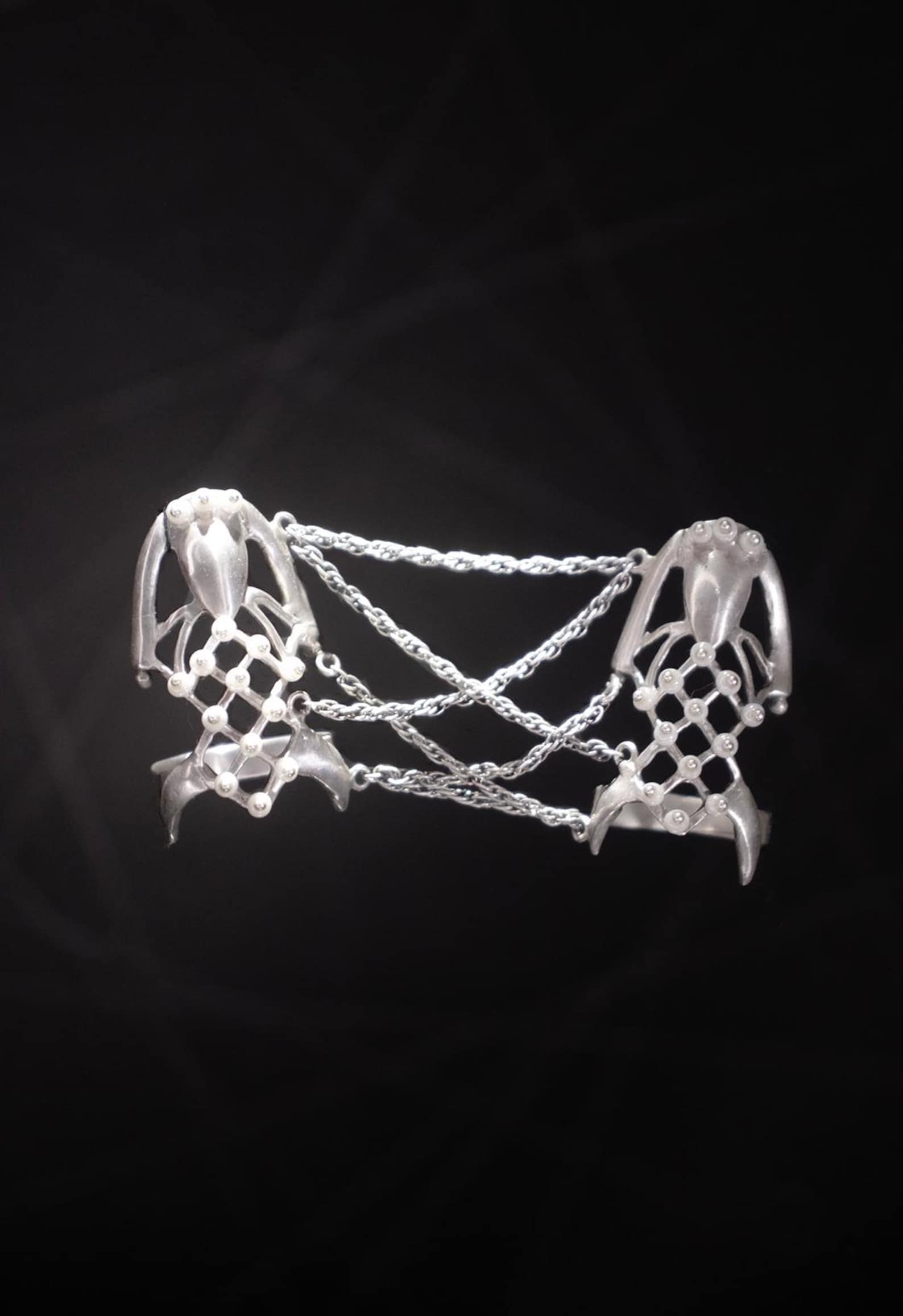 Close-up of silver spider-inspired finger chain ring with netted lattice and delicate chains