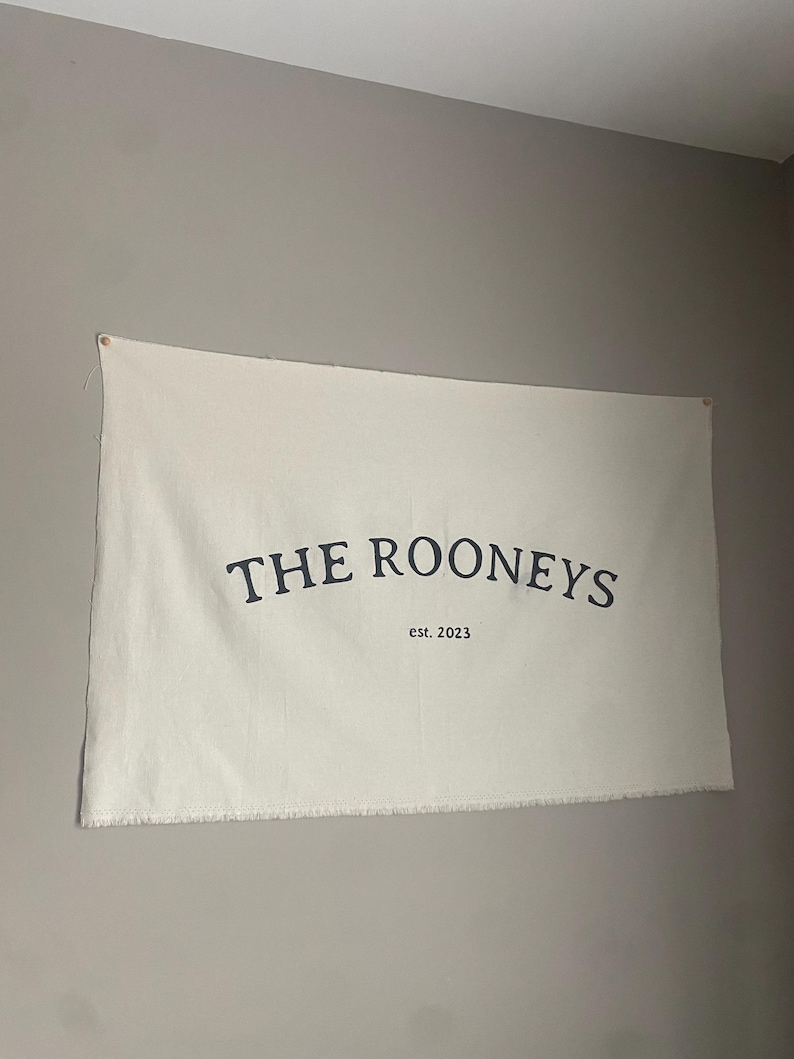 May include: A white canvas banner with black text that reads "THE ROONEYS est. 2023".