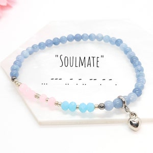 May include: A light blue beaded bracelet with a pink and blue section and a silver heart charm. The bracelet has the word "SOULMATE" written on it and the word in morse code.