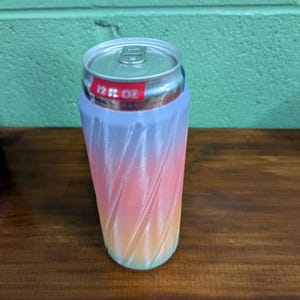 Pu&ograve; includere: Un portabevande color cotone filato con una sfumatura di rosa, arancione e blu. Il portabevande contiene una lattina da 355 ml. Il testo "Cotton Candy" &egrave; in basso nell'immagine.