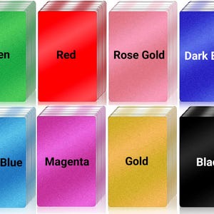 May include: Eight stacks of playing cards in various colors: green, red, rose gold, dark blue, light blue, magenta, gold, and black. Each stack has the color name printed in white.
