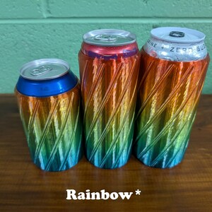 Pu&ograve; includere: Tre refrigeratori per lattine color arcobaleno con un design a spirale. I refrigeratori sono nelle tonalit&agrave; di blu, verde, giallo, arancione e rosso. Il testo "Rainbow *" &egrave; in basso nell'immagine.