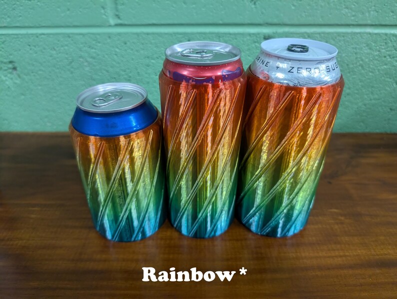 Pu&ograve; includere: Tre refrigeratori per lattine color arcobaleno con un design a spirale. I refrigeratori sono nelle tonalit&agrave; di blu, verde, giallo, arancione e rosso. Il testo "Rainbow *" &egrave; in basso nell'immagine.