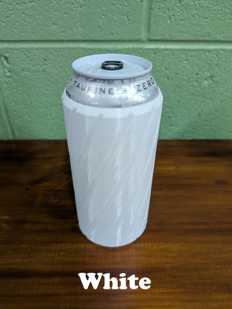Pu&ograve; includere: Un portabevande bianco con un design a spirale, che contiene una lattina di bevanda. La lattina ha il testo "TAURINE ZERO" stampato sopra. La parola "White" &egrave; visualizzata nella parte inferiore dell'immagine.