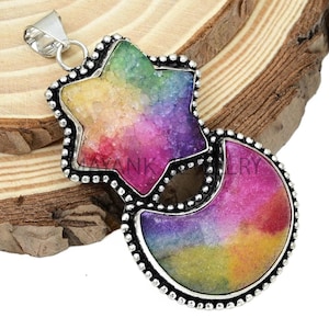 Puede incluir: Un colgante de plata con un diseño de estrella y luna creciente de colores arcoíris. La estrella y la luna están engastadas en un marco de plata con un borde de cuentas.