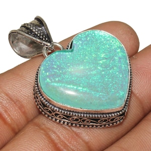 May include: A silver heart-shaped pendant with a light blue opal gemstone. The pendant has an intricate silver design around the edge.