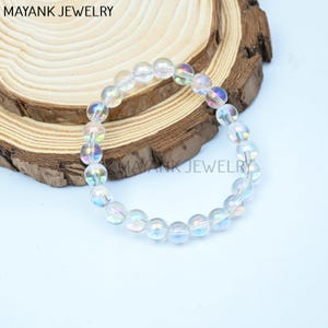May include: A white iridescent crystal bead bracelet. The beads are round and have a rainbow sheen.