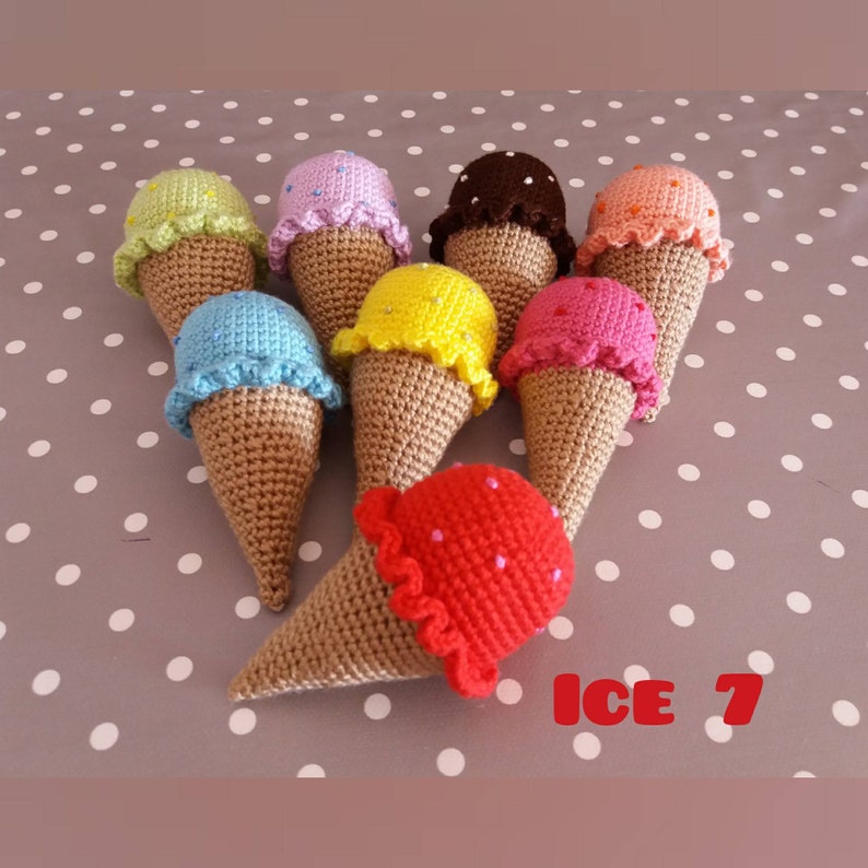 May include: A collection of eight crocheted ice cream cones in various colors, including pink, blue, yellow, green, red, brown, and orange. Each cone has a different colored ice cream scoop with white polka dots. The text "ICE 7" is visible in the lower right corner of the image.