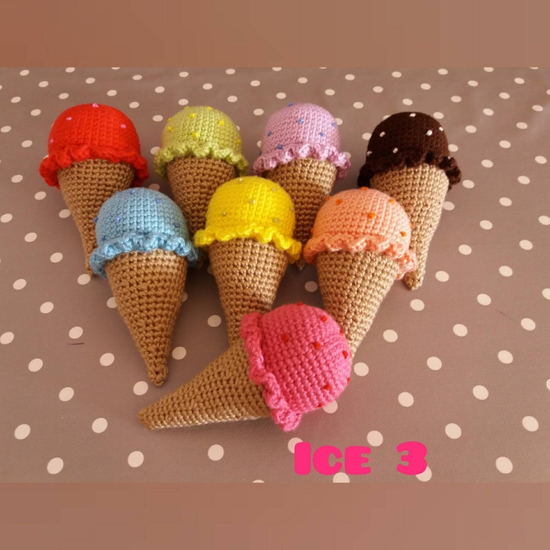 May include: A collection of eight crocheted ice cream cones in various colors, including red, yellow, blue, green, pink, orange, brown, and purple. The cones are arranged in a circle on a white and gray polka dot background. The text "ICE 3" is written in pink letters below the cones.