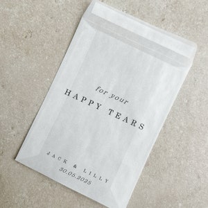 May include: White paper envelope with the text "for your HAPPY TEARS" and "JACK & LILLY 30.05.2025" printed on it.
