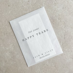 May include: White tissue paper envelope with the text "for your HAPPY TEARS" and "JACK & LILLY 30.05.2025" printed in black.