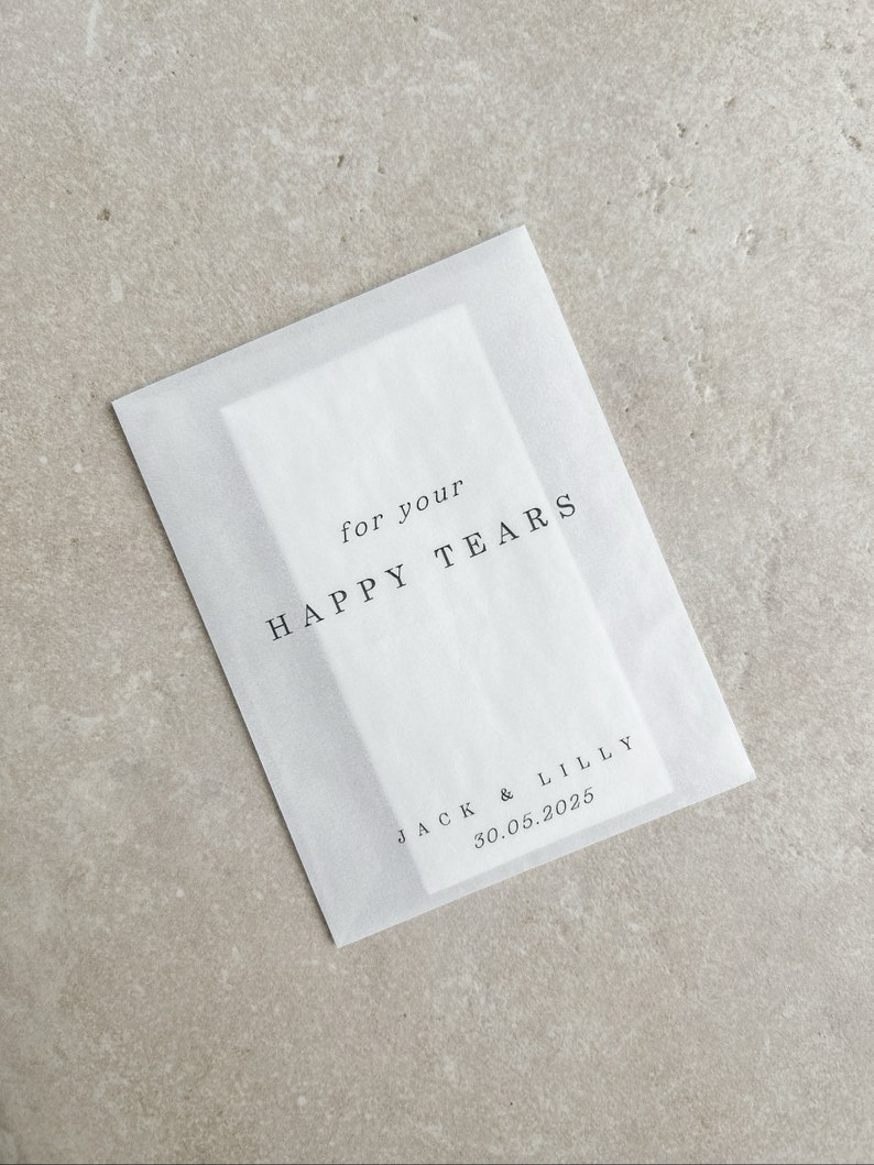 May include: White tissue paper envelope with the text "for your HAPPY TEARS" and "JACK & LILLY 30.05.2025" printed in black.