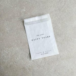 May include: White envelope with the text "for your HAPPY TEARS" and "JACK & LILLY 30.05.2025" printed on it.