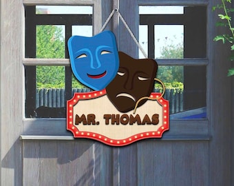 Puede incluir: Un letrero de madera para puerta con un diseño de marquesina rojo, blanco y azul. El letrero presenta dos máscaras teatrales, una sonriente y otra frunciendo el ceño, y el texto "MR. THOMAS".