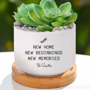 May include: White ceramic planter with a succulent plant and the text "NEW HOME NEW BEGINNINGS NEW MEMORIES The Smiths".