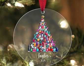 May include: A clear round Christmas ornament with a colorful nail polish tree design. The tree is made up of many different colored nail polish bottles. The ornament has the name "Taylor" and the year "2024" written on it.