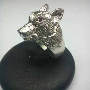 May include: A silver wolf head ring with a red gemstone eye.