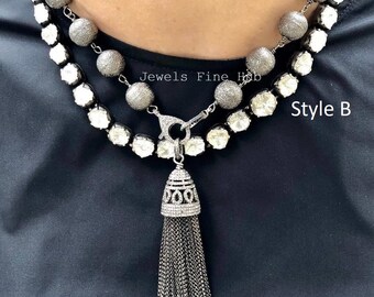 Puede incluir: Collar de dos hilos con acabado plateado. La hebra superior presenta cuentas redondas texturizadas, mientras que la hebra inferior tiene piedras claras y facetadas. El estilo B incluye un colgante de borla. El texto "Jewels Fine Hub" es visible.