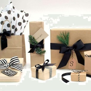 Puede incluir: Una variedad de regalos envueltos en varios tama&ntilde;os y formas. Los regalos est&aacute;n envueltos en papel y cajas marrones, adornados con cintas y lazos negros. Algunos regalos tienen etiquetas decorativas y vegetaci&oacute;n.