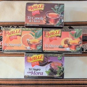 May include: Four boxes of Valle Premium Cusco tea. The boxes are red, white, and green with images of teacups, fruit, and flowers. The tea flavors are: Canela & Clavo, Naranja, Durazno, and Negro con Mora. Each box contains 25 tea bags.