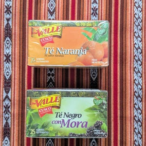 May include: Two boxes of tea bags, one orange and one green. The orange box says "Valle Premium Cusco La Convencion Te Naranja Te sabor naranja 25 Sobres Filtrantes Peso Neto 32.5g". The green box says "Valle Premium Cusco La Convencion Te Negro con Mora 25 Sobres Filtrantes Peso Neto 25g".
