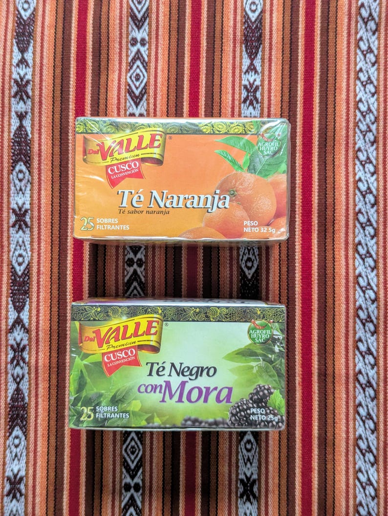 May include: Two boxes of tea bags, one orange and one green. The orange box says "Valle Premium Cusco La Convencion Te Naranja Te sabor naranja 25 Sobres Filtrantes Peso Neto 32.5g". The green box says "Valle Premium Cusco La Convencion Te Negro con Mora 25 Sobres Filtrantes Peso Neto 25g".
