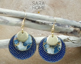 May include: Gold and blue patterned earrings with a floral design. The earrings are made of two round layers with a gold circle on top. The earrings are hanging from a gold hook.