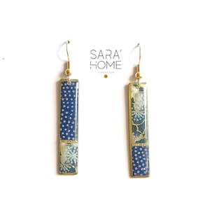Puede incluir: Un par de pendientes de oro con colgantes rectangulares con patrones azules y blancos. Los pendientes están hechos por SARA' HOME CREATION.