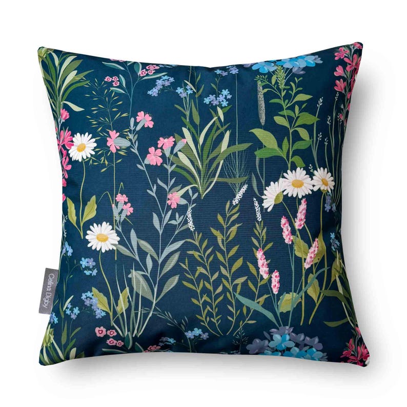 May include: A blue throw pillow with a floral pattern featuring pink, white, and green flowers. The pillow has a dark blue background and a white border.