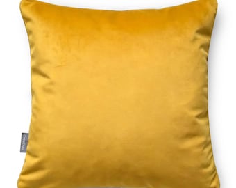 May include: A square throw pillow in a solid mustard yellow color with a soft velvet texture. The pillow features a small grey fabric tag on the left side with the text Celina Digby printed in white, indicating the brand name on the item.
