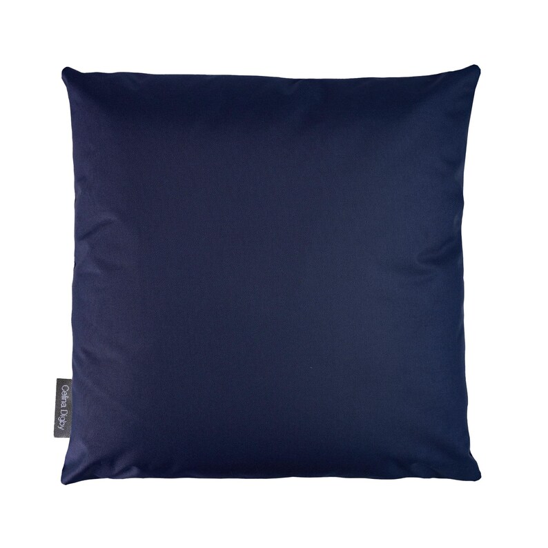 May include: A dark blue square pillow with a small white label that says "Cotta Design" in the bottom left corner.