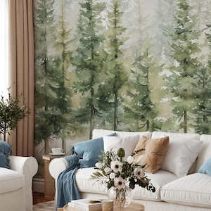 May include: A living room scene featuring a white sofa with blue and tan pillows, a wooden coffee table, and a watercolor forest mural. A vase of white flowers sits on the table. The room has a cozy, natural aesthetic.