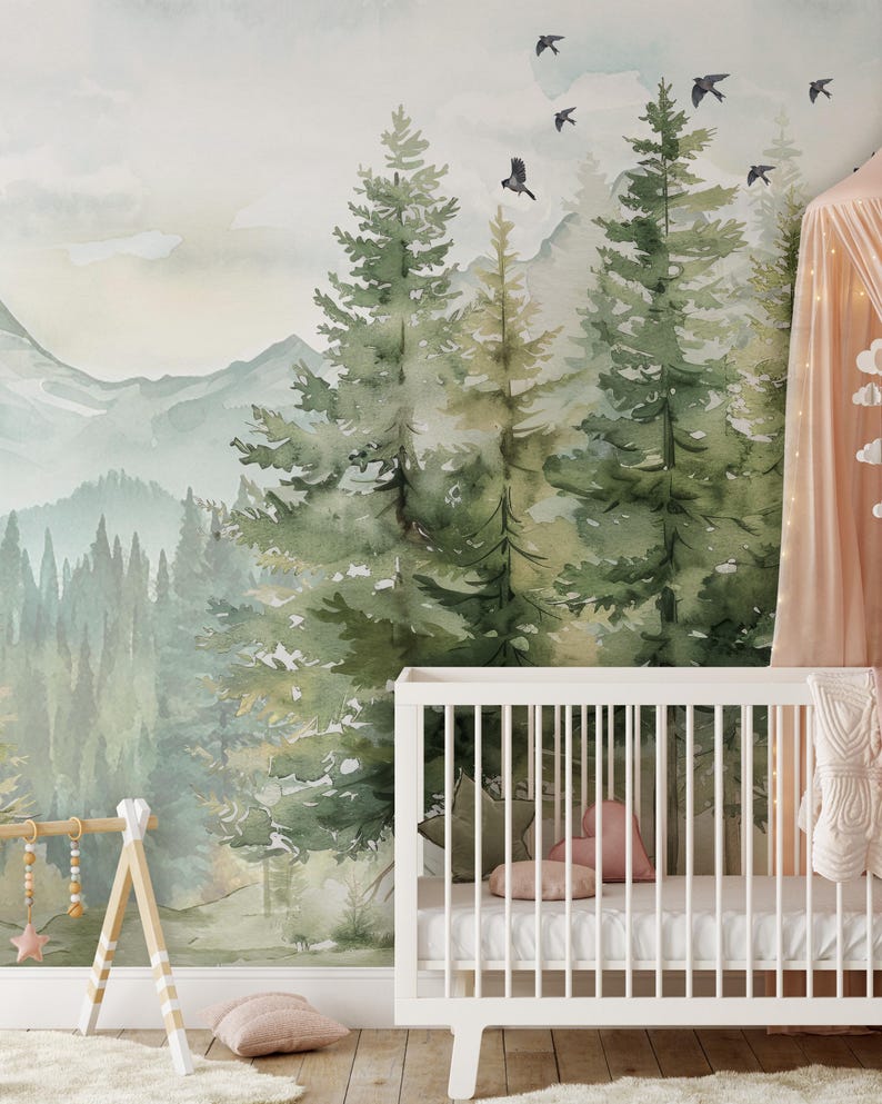 May include: A nursery with a forest-themed mural featuring watercolor trees, mountains, and flying birds. A white crib with a white mattress, pillows, and a blanket is in the foreground. A wooden baby gym and a pink canopy add to the decor.