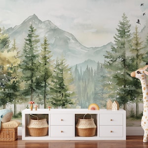 May include: A whimsical nursery scene featuring a mountain and forest mural. A white cabinet holds woven baskets and decorative items. A plush giraffe and whale add playful elements to the room. The color palette includes greens, browns, and whites.