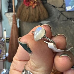 May include: A silver ring with a large oval-shaped moonstone. The stone is iridescent and has a milky white color.