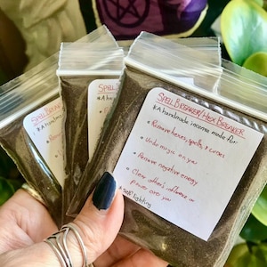May include: Three small plastic bags filled with brown incense powder. The bags have handwritten labels that say "Spell Breaker/Hex Breaker" and list the uses of the incense, including removing hexes, spells, and curses, undoing magic, removing negative energy, and clearing other's influence or power over you. The label also says "A handmade incense made for:" and "self lighting".