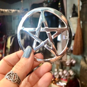 May include: A silver pentagram pendant with a five-pointed star design. The pendant is circular and has a smooth, polished finish.