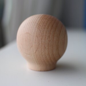 May include: A light brown wooden sphere with a smooth, slightly textured surface.