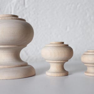 May include: Three wooden knobs of varying sizes. The largest knob is approximately 10 cm tall and has a rounded top. The middle knob is approximately 5 cm tall and has a rounded top. The smallest knob is approximately 2.5 cm tall and has a rounded top.