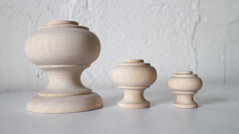 May include: Three wooden knobs of varying sizes. The largest knob is approximately 10 cm tall and has a rounded top. The middle knob is approximately 5 cm tall and has a rounded top. The smallest knob is approximately 2.5 cm tall and has a rounded top.