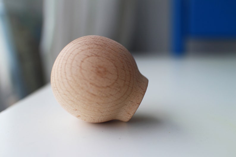 May include: A round, wooden knob with a smooth, light brown finish. The knob has a slightly rounded top and a flat bottom.