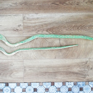 Puede incluir: Dos serpientes de juguete de madera en un suelo de madera. La serpiente m&aacute;s grande mide 90 cm/35 pulgadas de largo y la serpiente m&aacute;s peque&ntilde;a mide 60 cm/23 pulgadas de largo.