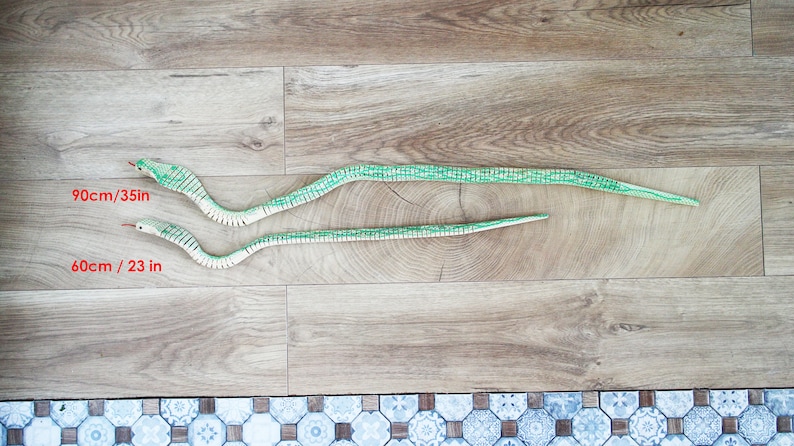 Puede incluir: Dos serpientes de juguete de madera en un suelo de madera. La serpiente m&aacute;s grande mide 90 cm/35 pulgadas de largo y la serpiente m&aacute;s peque&ntilde;a mide 60 cm/23 pulgadas de largo.