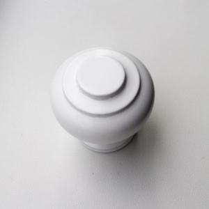 May include: White ceramic knob with a rounded top and a slightly raised rim. The knob has a smooth, glossy finish.