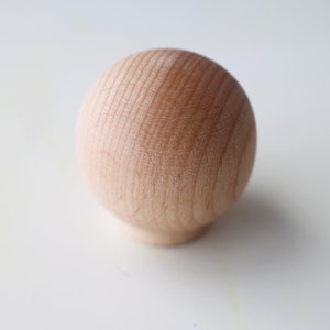 May include: A smooth, round wooden knob with a natural wood finish.