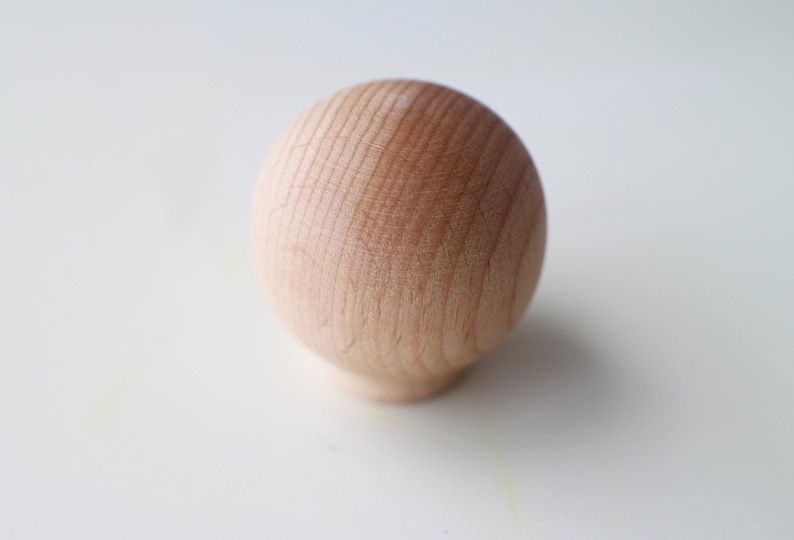 May include: A smooth, round wooden knob with a natural wood finish.