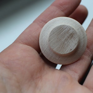 Op de afbeelding: Een ronde houten knop met een verhoogd midden, perfect om meubels of knutselwerk een rustieke uitstraling te geven.