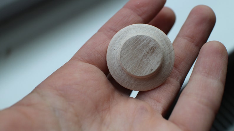 Op de afbeelding: Een ronde houten knop met een verhoogd midden, perfect om meubels of knutselwerk een rustieke uitstraling te geven.