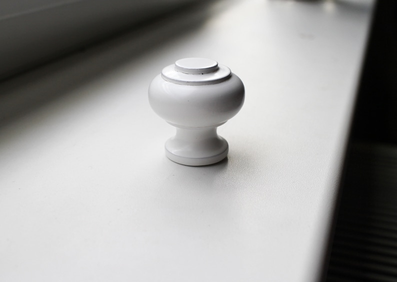 May include: White ceramic knob with a rounded top and a slightly flared base.